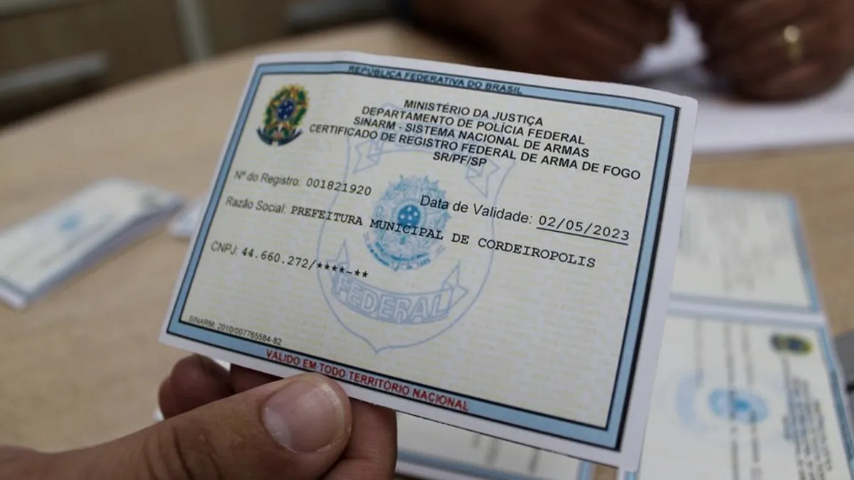 Mãos segurando certificado de registro de arma de fogo emitido pela Polícia Federal